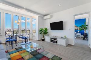 a living room with a television and a table and chairs at Sky Suites Alicante in Alicante