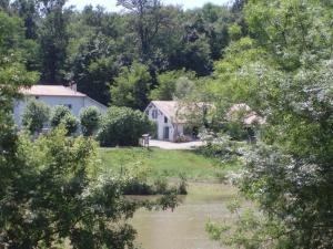 a house next to a river with trees at Les barthes in Orist +6 photos