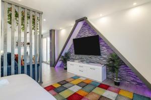 1 dormitorio con TV y pared de ladrillo en Sky Suites Alicante, en Alicante