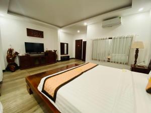 a bedroom with a large bed and a flat screen tv at Jen Hotel in Tuy Hoa