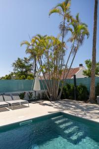 a pool with two chairs and a umbrella and palm trees at Vivienda Vacacional Pasito Blanco 1 in Pasito Blanco