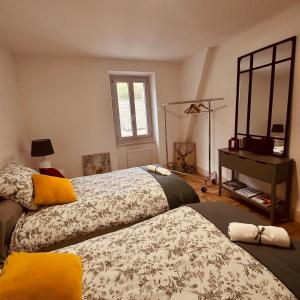 a bedroom with two beds and a dresser and a mirror at AMPLE Conciergerie in Cierp