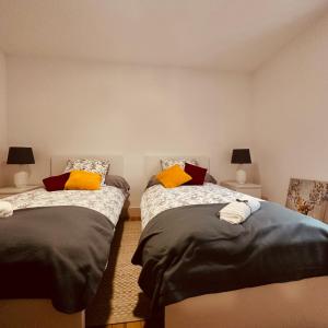 een slaapkamer met 2 bedden en gele kussens bij AMPLE Conciergerie in Cierp