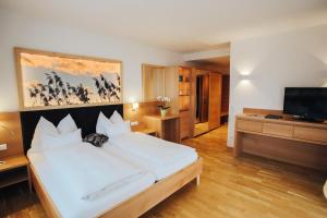 a bedroom with a large bed and a flat screen tv at Hotel SeeRose in Bodensdorf