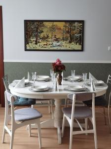 una mesa de comedor blanca con sillas y una pintura en Wodna Ostoja z kominkiem nad jeziorem Selment, en Buczki