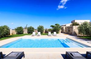 une piscine avec deux chaises longues et une villa dans l'établissement Masseria Specchia, à Lecce