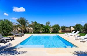 une piscine avec des chaises longues et une piscine dans l'établissement Masseria Specchia, à Lecce