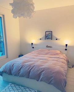 ein Schlafzimmer mit einem Bett mit zwei Leuchten in der Unterkunft Lakeside Modern Minimalist Apartment FreeParking in Järvenpää