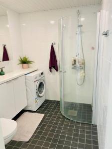a bathroom with a shower and a washing machine at Lakeside Modern Minimalist Apartment FreeParking in Järvenpää
