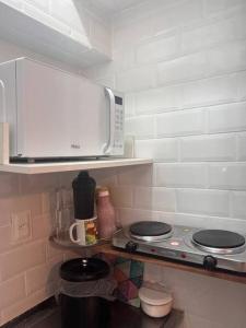a kitchen with a stove and a microwave on a shelf at Loft no coração da Lapa in Rio de Janeiro