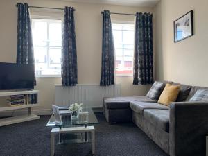 a living room with a couch and a tv at Market Place Serviced Apartments, Leek in Leek