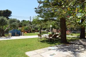 Simatos αpARTments & Studios في لاسي: طاولة وكراسي تحت شجرة في حديقة