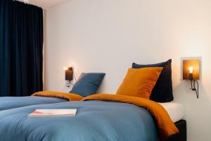 - une chambre avec 2 lits dotés d'oreillers orange et bleu dans l'établissement Befour Vakantiewoning, à Aalst