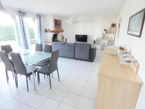 uma cozinha e sala de estar com uma mesa de vidro e cadeiras em Deze bis em Herm