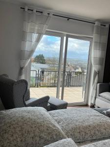 - une chambre avec un lit, des chaises et une grande fenêtre dans l'établissement Rheinview Sunset in Urbar, à Urbar