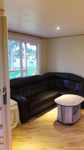 sala de estar con sofá de cuero negro y mesa en Namelis sodyboje Lazduona, 