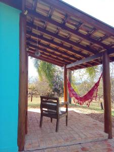 a bench under a wooden pergola with a hammock at Chalés Quinta da Nascente - Serra da Canastra in Delfinópolis