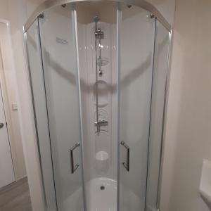 a shower with a glass enclosure in a bathroom at Chalet Weizicht op minicamping Hoogelande in Grijpskerke
