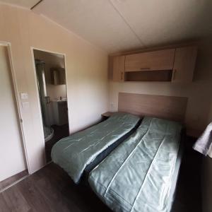 um quarto com uma cama num pequeno quarto em Chalet Weizicht op minicamping Hoogelande em Grijpskerke
