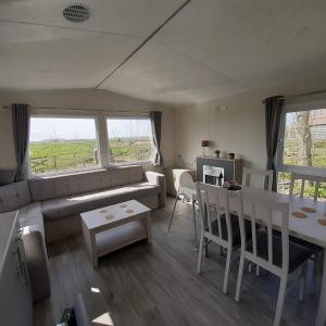 uma sala de estar com um sofá e uma mesa em Chalet Weizicht op minicamping Hoogelande em Grijpskerke