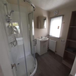 uma casa de banho com um chuveiro e um lavatório. em Chalet Weizicht op minicamping Hoogelande em Grijpskerke