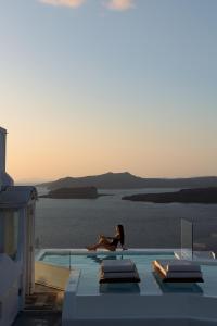 a woman sitting on the edge of a swimming pool at Caldera View Private Villa in Megalochori