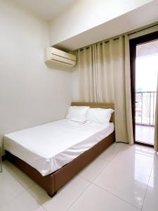 a bedroom with a bed and a window at Admiral Baysuites 1 BR Unit in Manila