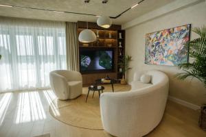 a living room with a white couch and a tv at Penthouse Lebada Lake View in Pantelimon +76 photos