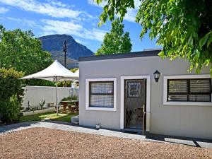 een grijs huis met een tafel en een paraplu bij La Rochelle Cottage in Franschhoek