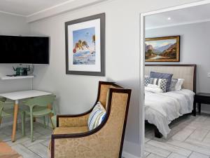 een slaapkamer met een bed, een tafel en een bureau bij La Rochelle Cottage in Franschhoek