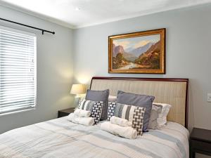 een slaapkamer met een bed met een schilderij aan de muur bij La Rochelle Cottage in Franschhoek