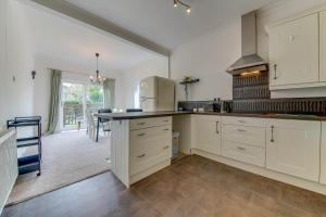 a kitchen with white cabinets and a table in it at Pass the Keys Cosy Bungalow in Sheffield in Sheffield