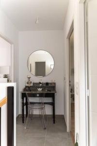 ein Bad mit einem Spiegel und einem Tisch mit einem Stuhl in der Unterkunft Maison de vacances chaleureuse à 600mdu Bassin in Andernos-les-Bains