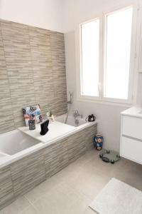 ein weißes Bad mit einer Badewanne und einem Fenster in der Unterkunft Maison de vacances chaleureuse à 600mdu Bassin in Andernos-les-Bains