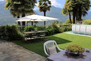 eine Terrasse mit einem Tisch und einem Sonnenschirm in der Unterkunft Casa Colori (C.I.R. 014051) in Poggiridenti