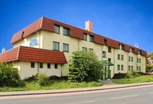 un gran edificio blanco con techo rojo en ACRON Hotel Wittenberg en Lutherstadt Wittenberg