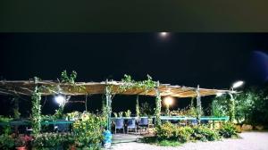 uma pérgola com mesas e cadeiras num jardim à noite em Villaggio dei Balocchi em Castelbuono