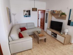 a living room with a white couch and a television at Villa Juanita, Puerto del Carmen, Lanzarote in Tías