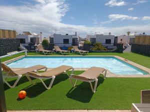 einen Pool mit zwei Liegestühlen und einem Ball in der Unterkunft Villa Juanita, Puerto del Carmen, Lanzarote in Tías