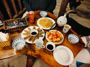 薩帕的住宿－Hmong Wooden Home，木桌,带盘子的食物和咖啡杯