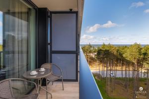 a balcony with a table and chairs and a view of the ocean at Shellter Apartments 117 J - by Jantar Apartamenty in Rogowo