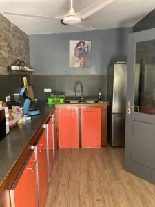 a kitchen with orange cabinets and a stainless steel refrigerator at Villa Aquarêve in Saly Portudal