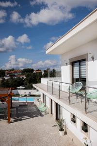 a balcony of a house with chairs and a swimming pool at Jasmine Hotel in São Pedro de Alva