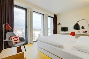 a bedroom with a large bed and a chair and windows at Smartcity Designhotel in Hannover