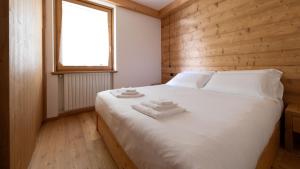 a bedroom with a bed with white sheets and a window at Sertorelli 27 in Bormio