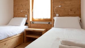 Duas camas num pequeno quarto com uma janela em Sertorelli 27 em Bormio