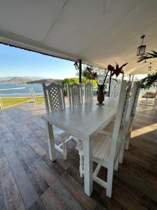 - une table et des chaises blanches sur une terrasse donnant sur l'océan dans l'établissement Casa Cabra Corral, à Coronel Moldes