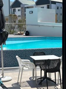 a table and chairs next to a swimming pool at Flat 2 Block 15 Bellamare in Port Elizabeth