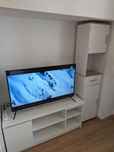 einen Flachbild-TV auf einem weißen Entertainment-Center in der Unterkunft Central spacious flat with private parking in Chamonix-Mont-Blanc