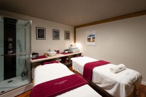 a hospital room with two beds and a bath tub at Hôtel Restaurant Spa Les Jardins De Sophie in Xonrupt-Longemer